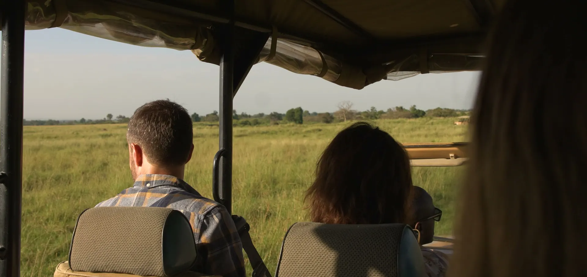 Two guests in an open safari vehicle looking out across the plains