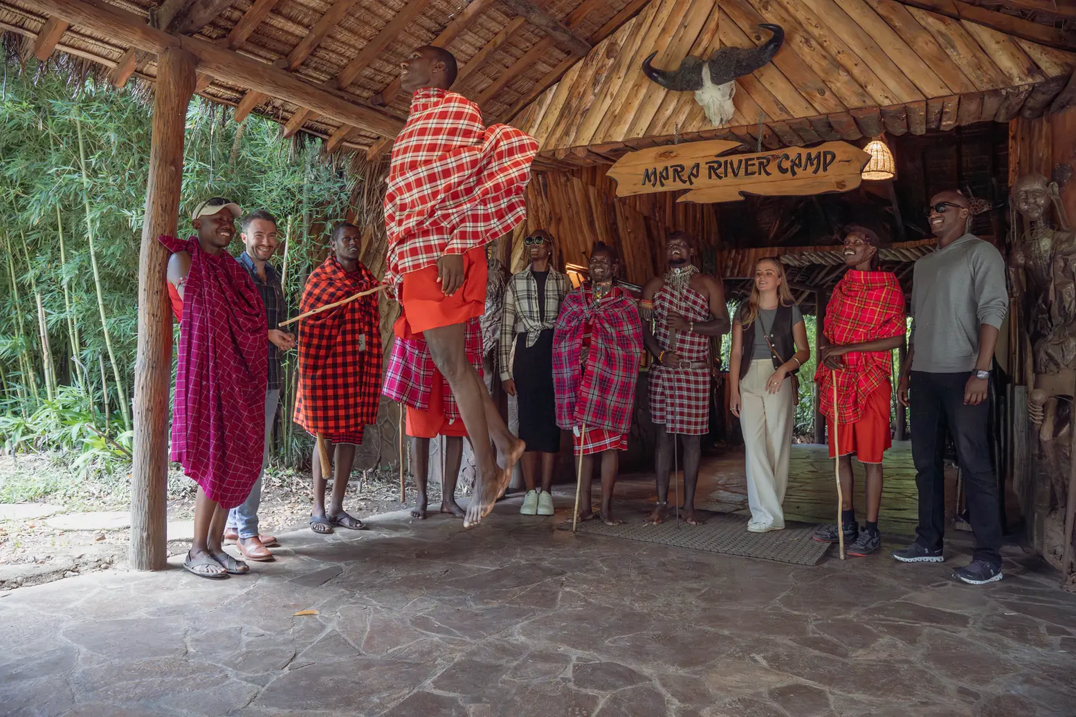 Maasai hosts in red shukas singing and jumping to welcome guests