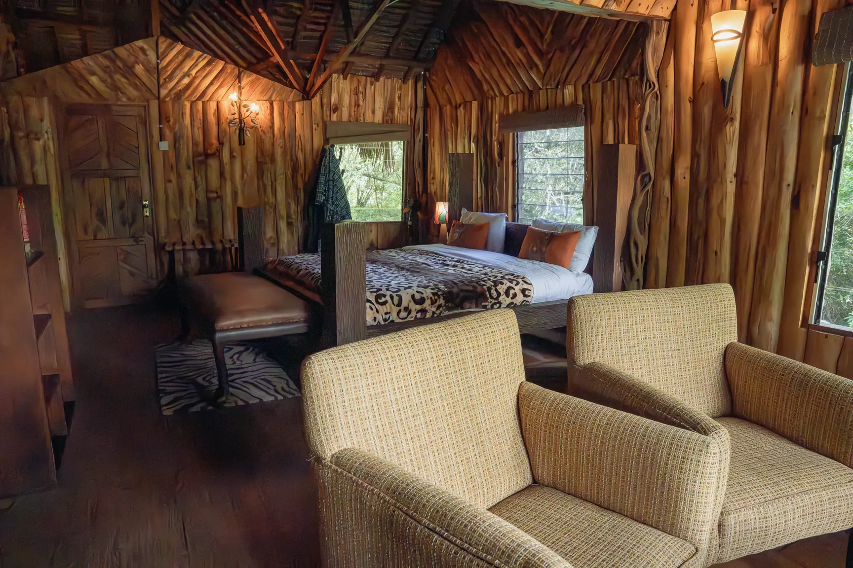 The living room of the two-bedroom log cabin, timber walls and lamplight